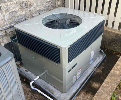 Outdoor HVAC unit installed near a stone wall.