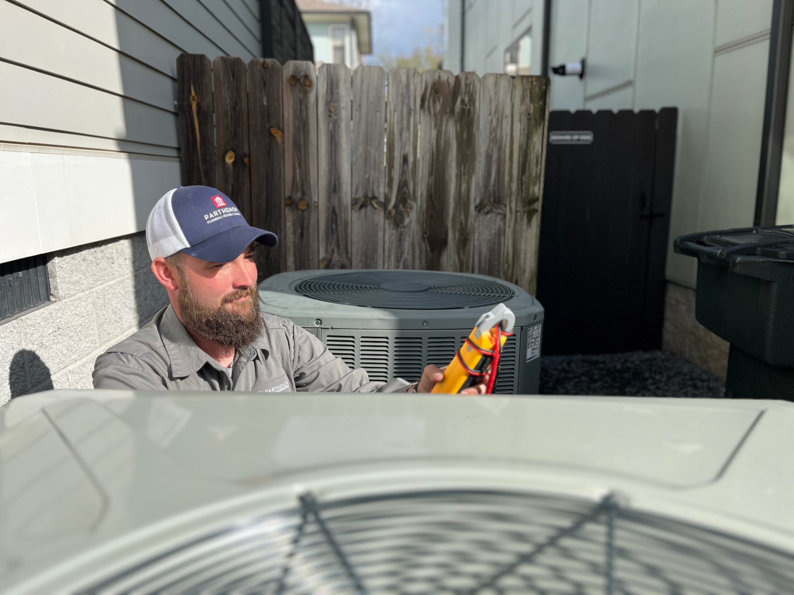 Technician inspecting an air conditioning unit outdoors