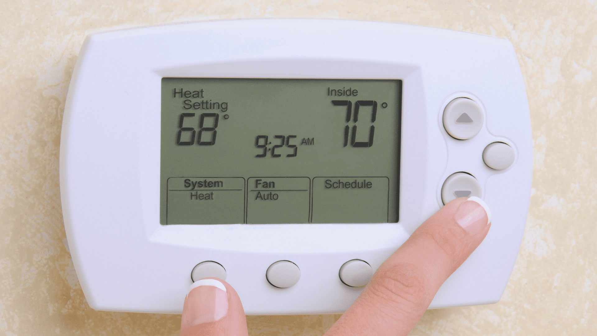 Person adjusting a thermostat set to 68°F heat