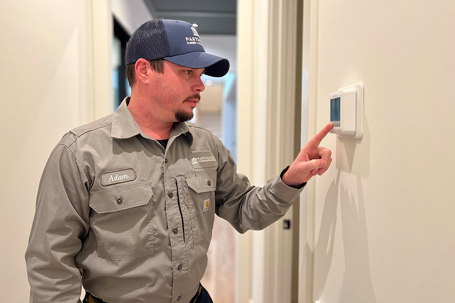 Parthenon technician setting thermostat in residential home