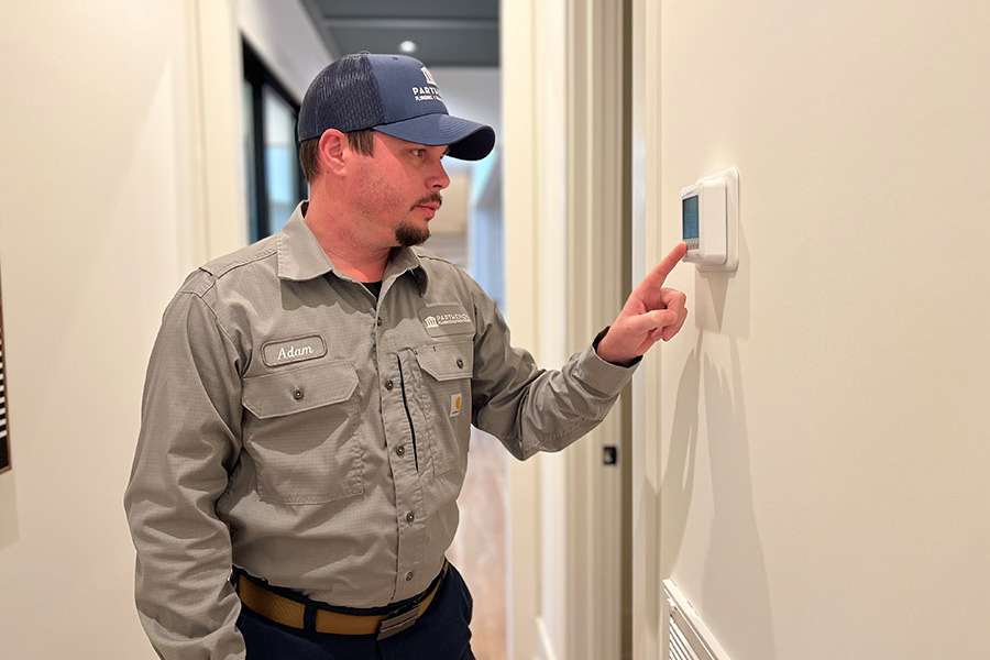 HVAC technician checking indoor thermostat for temperature