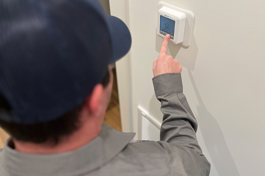 Technician setting temperature on wall thermostat