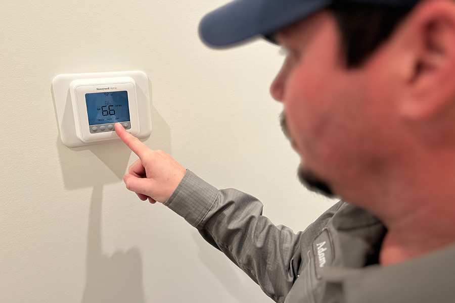 HVAC tech presses button on thermostat