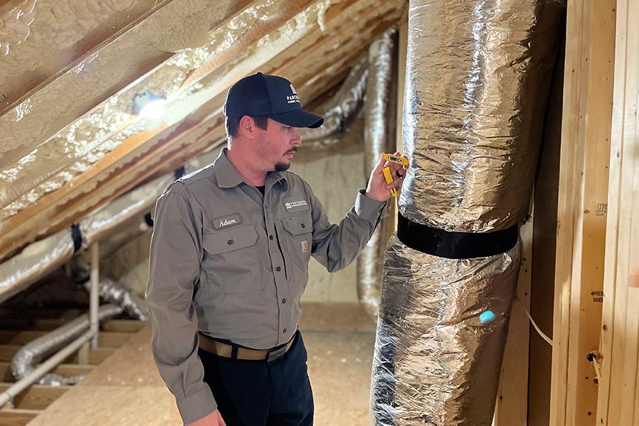 Technician inspects attic ductwork with a temperature tool