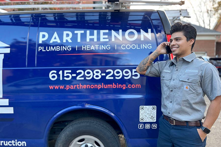 Parthenon Plumbing technician on phone next to service van