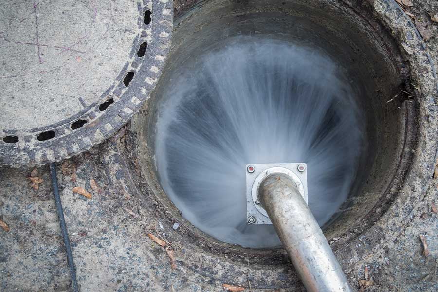 High-pressure water jet cleaning inside a sewer manhole