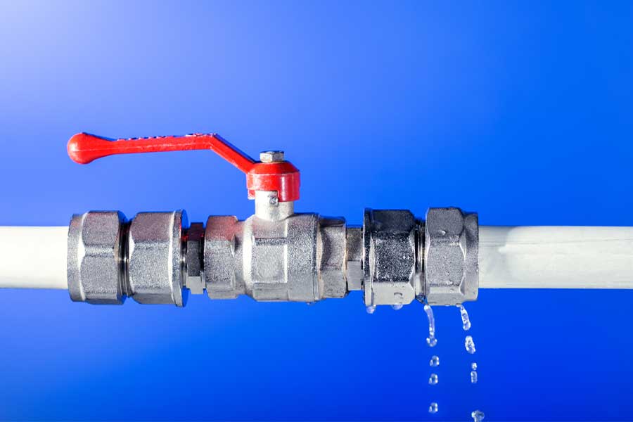Water dripping from a red-handled valve on a pipe.