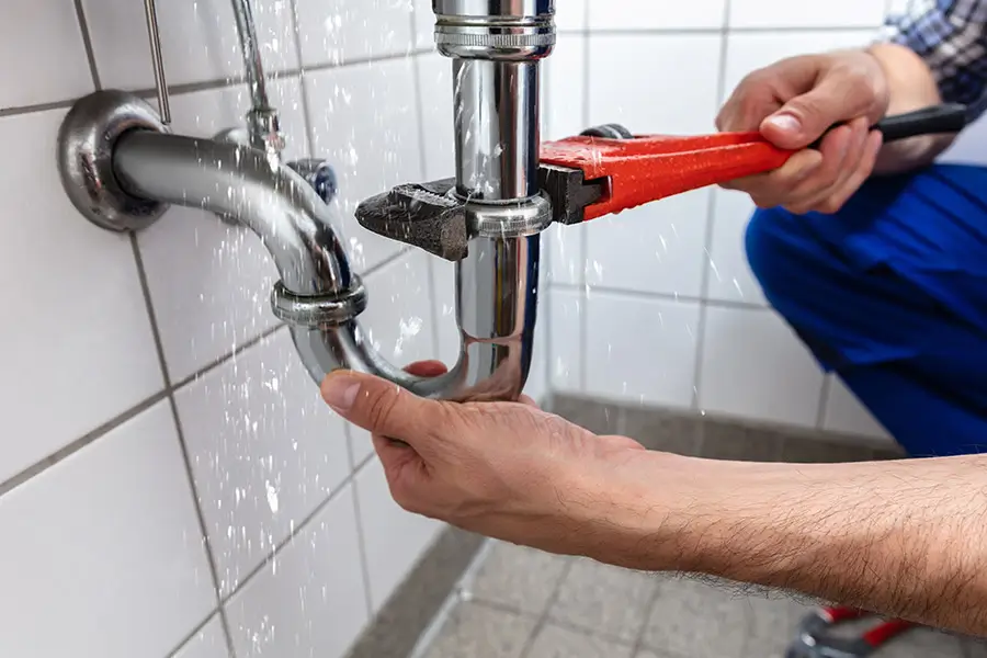 Person using pliers to tighten a faucet connection.