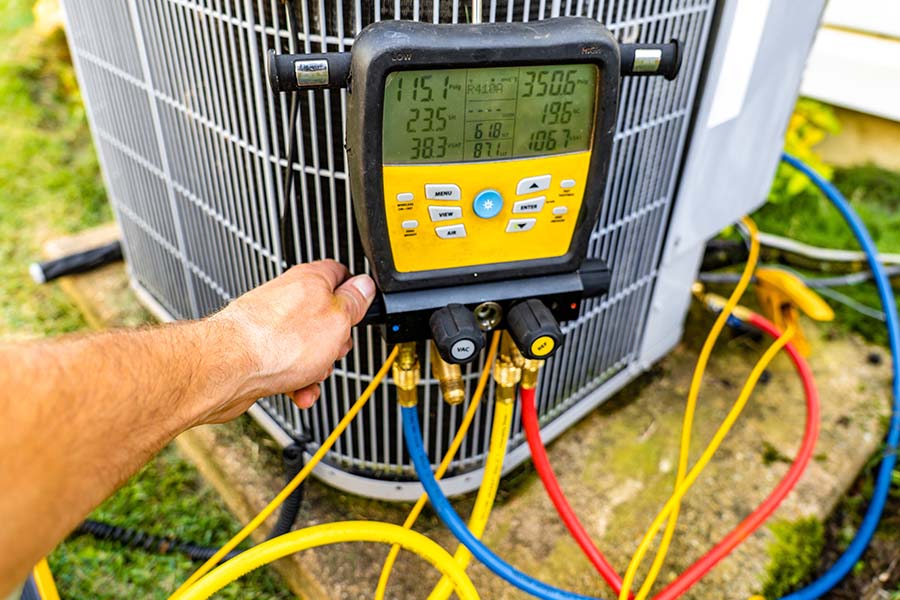 Technician using a digital gauge to test an HVAC unit.
